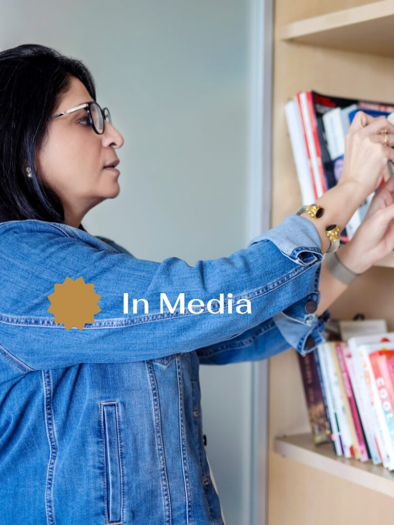 Anupam Bhatia selecting a book from a bookshelf, representing her media presence and holistic expertise at Anupam Holistic.