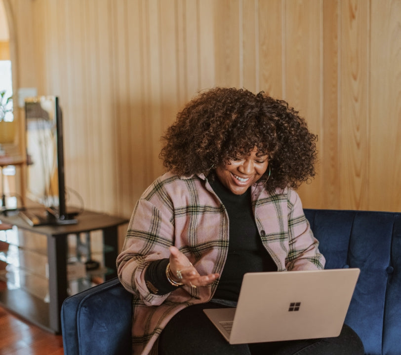 A woman smiling during an online consultation call on her laptop, representing Anupam Holistic's pre-consultation session.