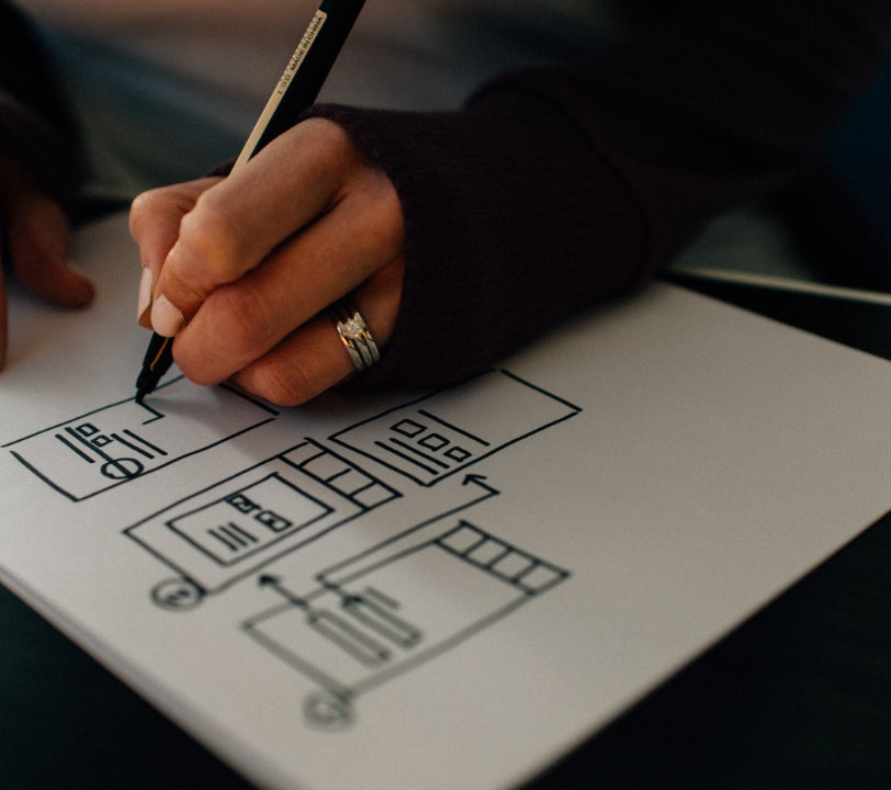 Close-up of a hand sketching a structured plan on paper, representing the personalized health plan process at Anupam Holistic.